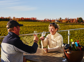 Couple à l'extérieur qui déguste un verre de vin au Vignoble de l'Orpailleur en automne.