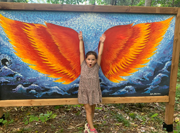 Jeune fille qui pose devant un panneau d'ailes.