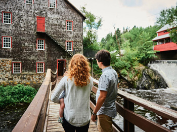 Jeune famille sur le pont devant le moulin à laine.