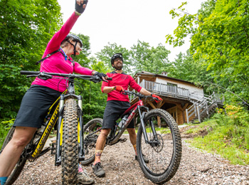 Deux cyclistes de montagne devant un chalet.