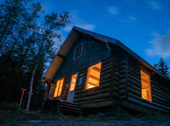 Refuge en forêt dans la nuit illuminé de l'intérieur.