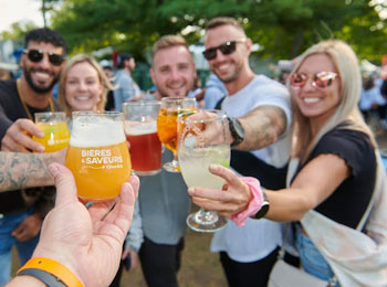 Groupe de personnes souriantes qui trinquent autour de leurs verres de bière.