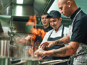 Trois hommes qui travaillent dans une cuisine industrielle.