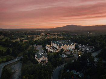 Vue panoramique du Domaine Château-Bromont avec le golf et la montagne en arrière-plan.