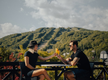 Couple qui partage un verre devant la montagne de ski en fin d'été.