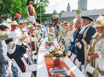 Invités en costume d'époque de Nouvelle-France autour d'une longue table.