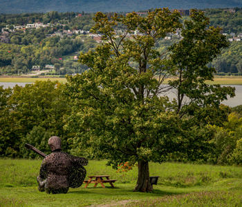 Sculpture représentant Félix Leclerc et paysage côtier de l'ile d'orléans.