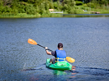 Homme de dos à la caméra en kayak sur le lac privé.