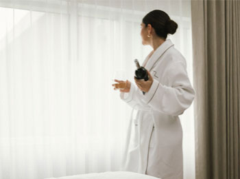 Femme en peignoir dans une chambre d'hôtel.