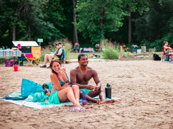 Couple aux visages heureux assis sur une serviette de plage.