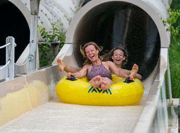 Une mère et son ado tout sourire au bas d’une glissade d’eau.