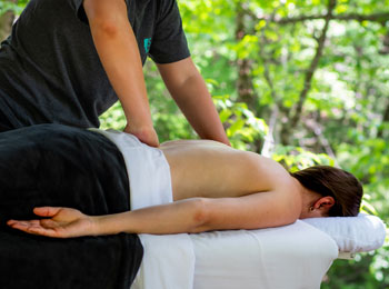 Femme en train de se faire masser le dos sur une table de massage.