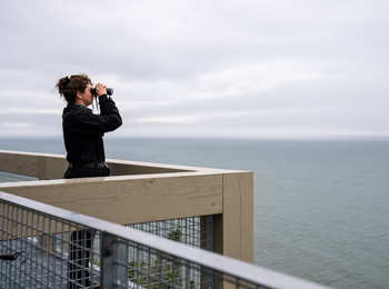 Femme qui observe la mer à l'aide de jumelles.