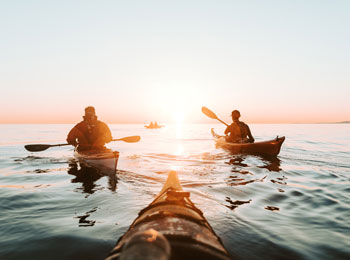 Groupe de kayakistes sur le fjord au coucher de soleil.