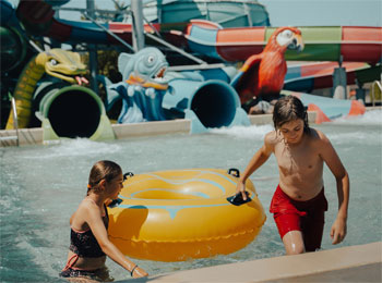 Jeune fille et jeune garçon avec un tube gonflable s'amusant dans une piscine.