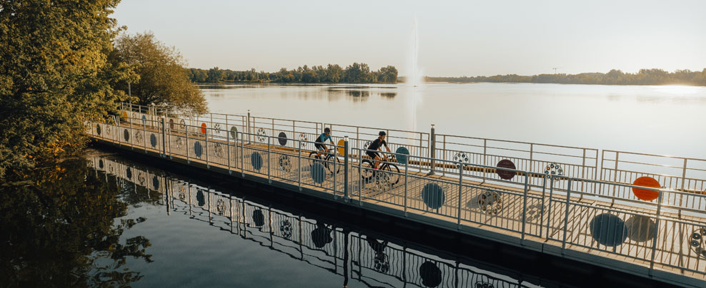 Deux cyclistes sur une piste cyclable au-dessus de l’eau.