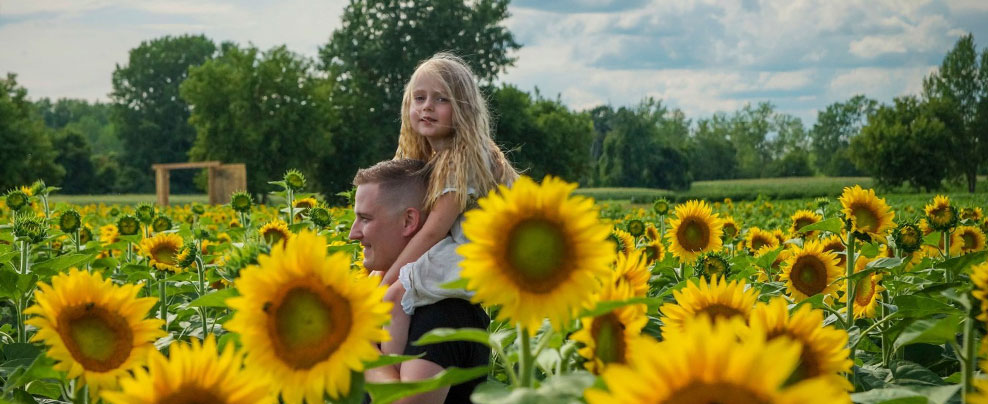 Père et fille dans un champ de tournesols à Laval.