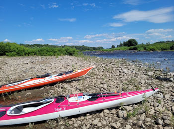 Deux kayaks sur la rive d’un cours d’eau.