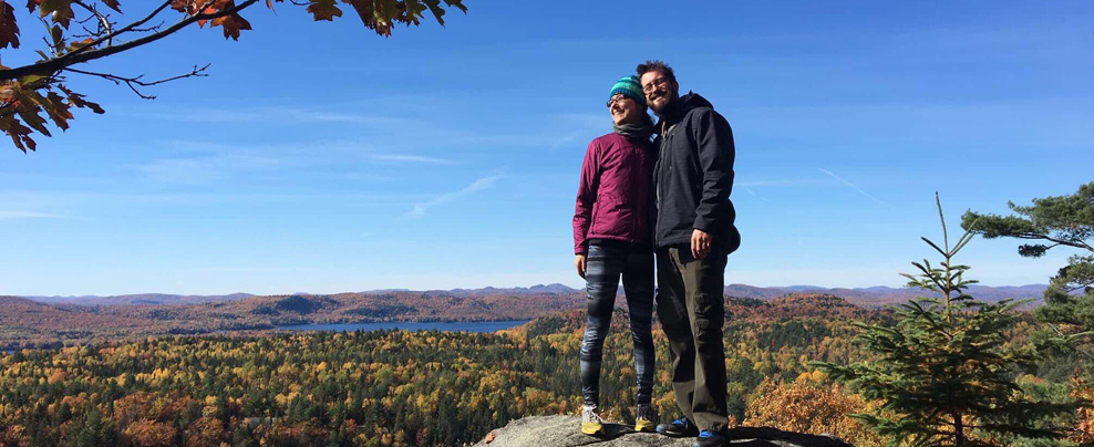 Deux personnes qui prennent la pose sur un rocher devant un paysage d’automne.