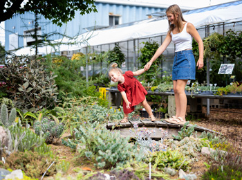 Mère et jeune fille devant un jardin de cactus.