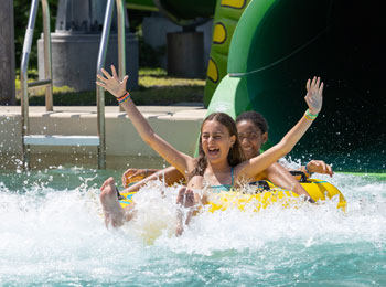 Deux jeunes filles à l’air joyeux au bas d’une glissade d’eau.